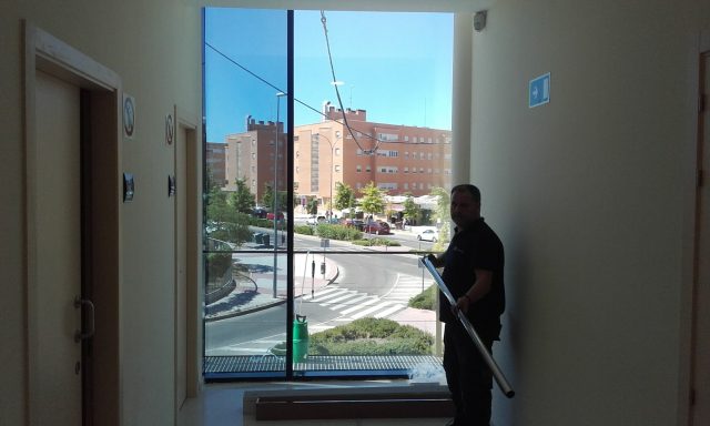 Un técnico se prepara para instalar láminas de tratamiento en la puerta de vidrio de un edificio, mejorando la eficiencia y la privacidad